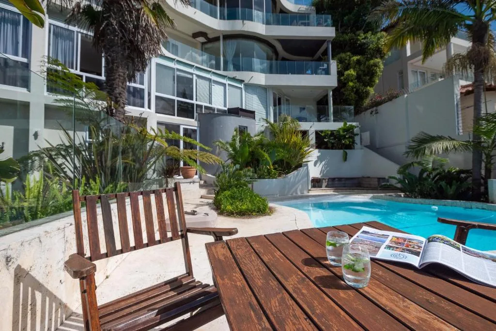 Swimming pool with wooden deck seating and tropical gardens surrounding the area