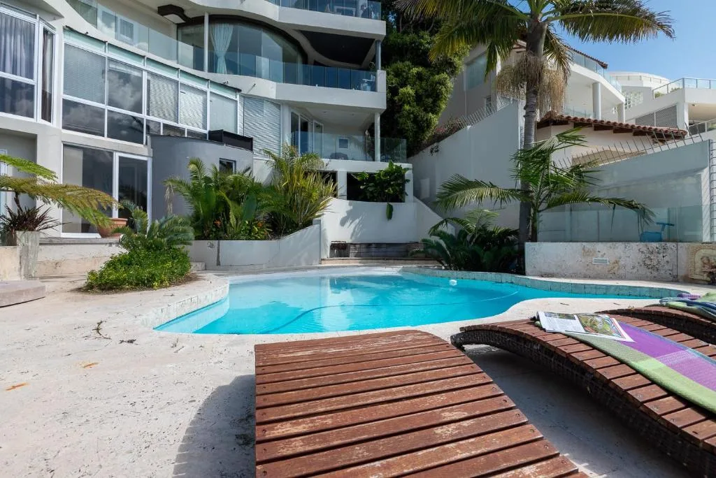 Sparkling blue swimming pool with sandy beach and modern apartment building