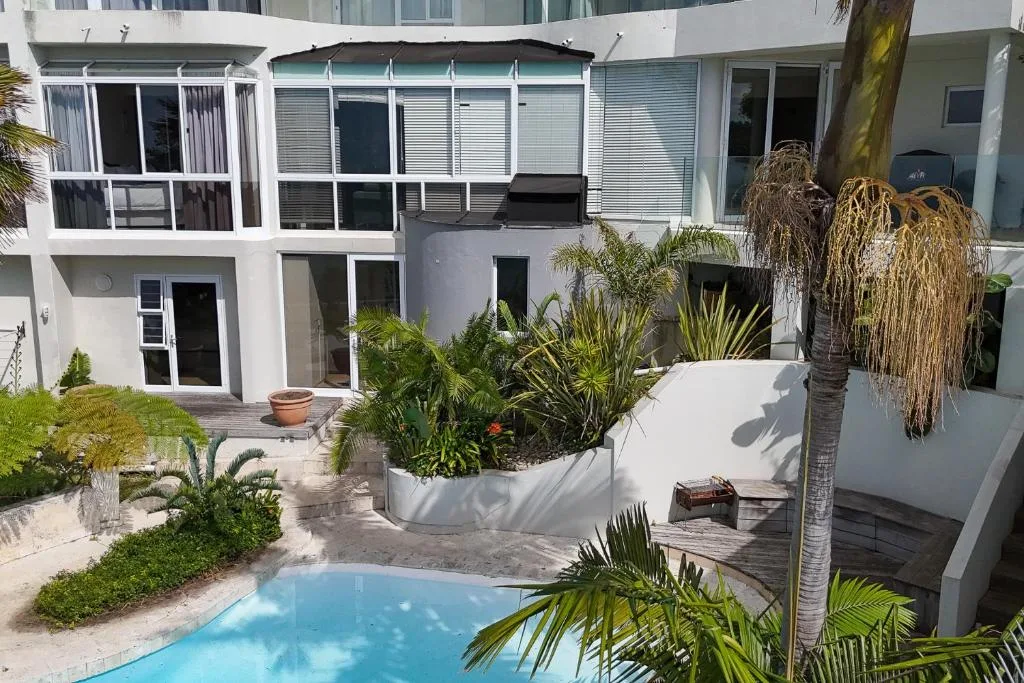 Bright blue swimming pool with modern white building and tropical garden landscaping