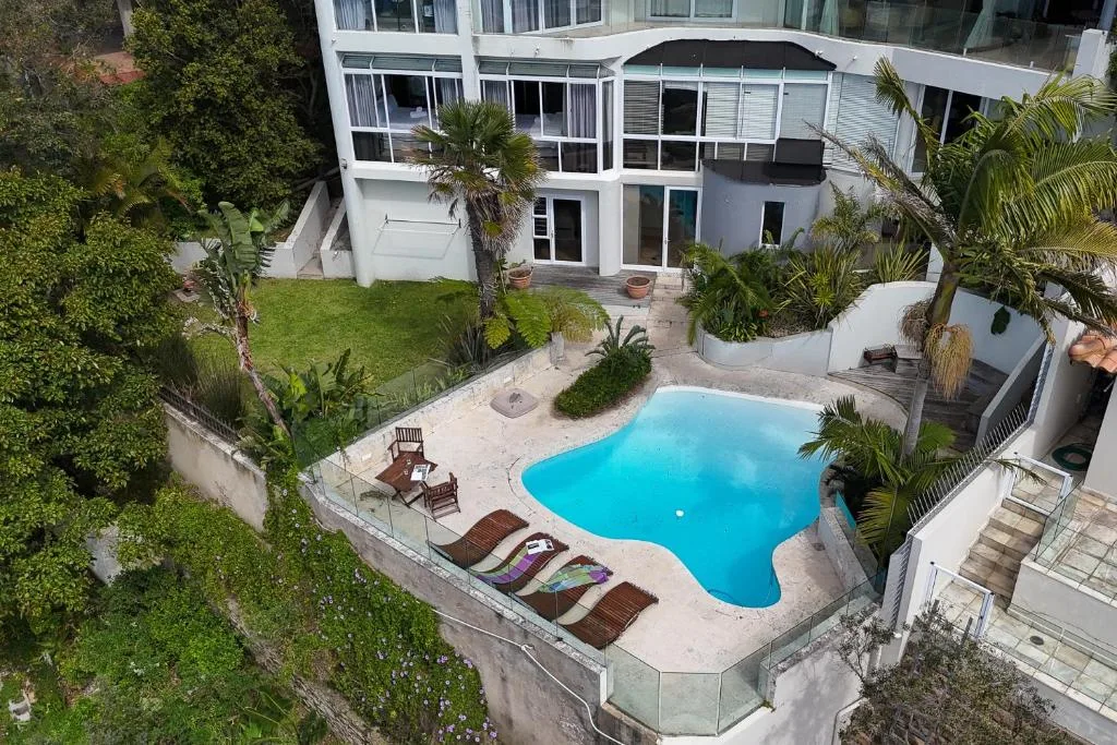 Bright turquoise swimming pool surrounded by loungers and lush tropical gardens