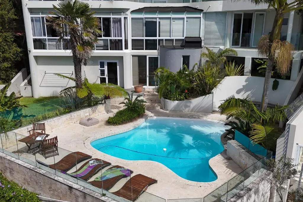 Sparkling blue swimming pool surrounded by lounge chairs and tropical plants