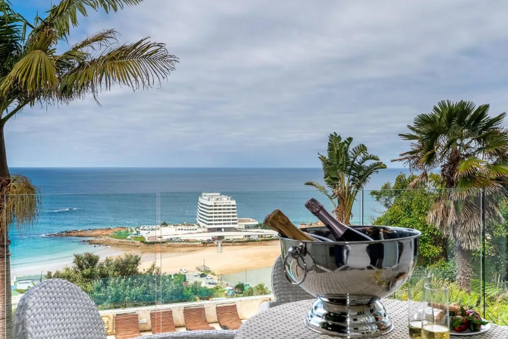 Coastal ocean view with beach, hotel, and palm trees from deck