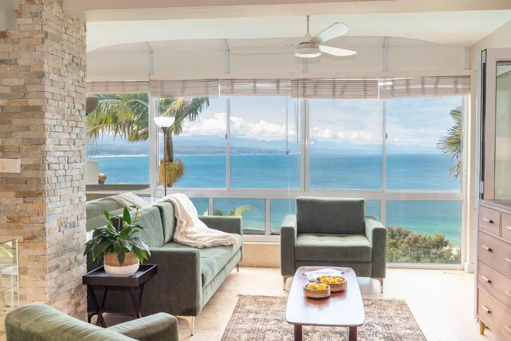 Expansive ocean and coastline views through floor-to-ceiling windows from comfortable lounge