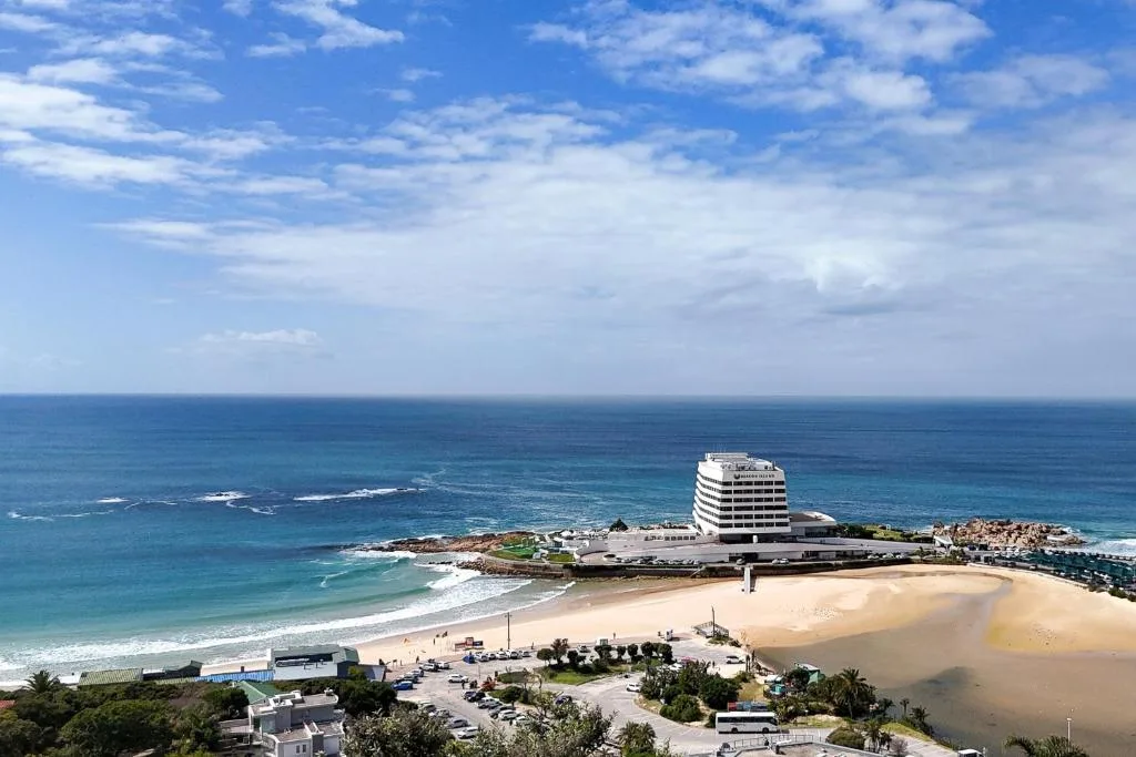 Coastal beach town vista with sandy shore, ocean, and beachfront hotel building
