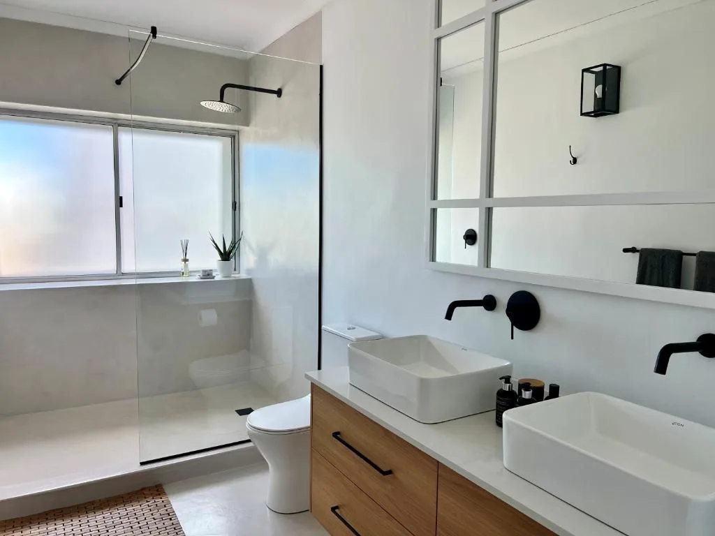 Modern bathroom with dual vessel sinks, rainfall shower, and large mirror