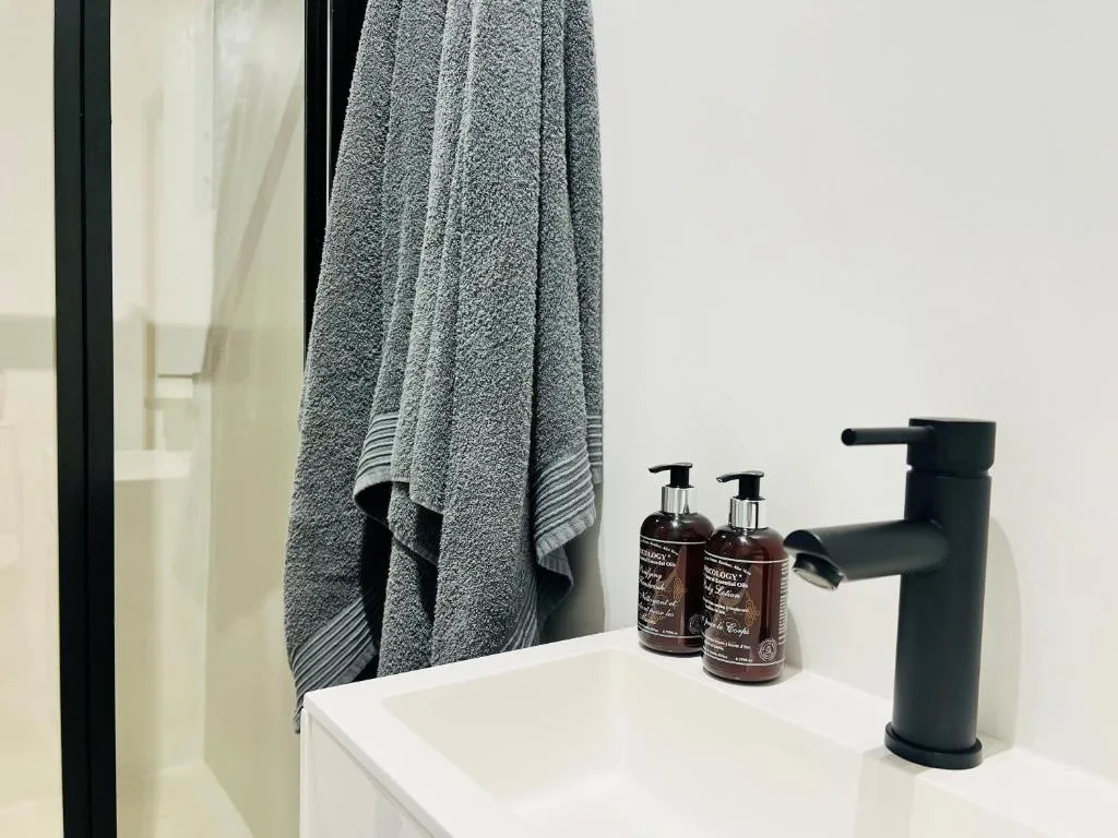 Modern bathroom vanity with black faucet, toiletries, and gray towel