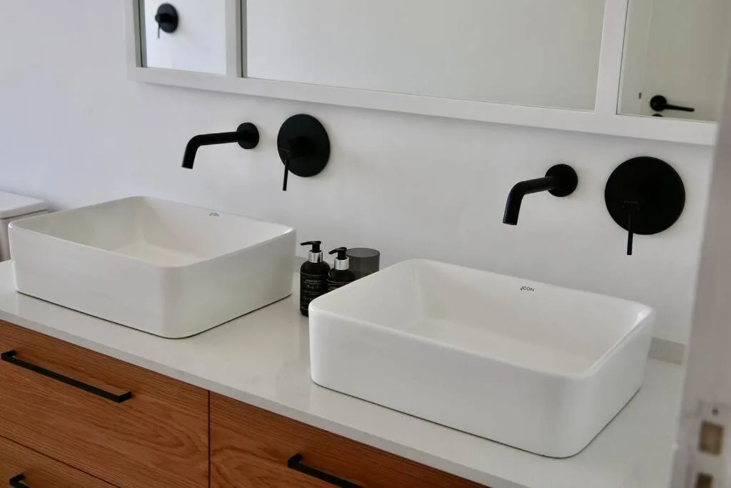 Modern dual vanity bathroom with white rectangular sinks and black fixtures