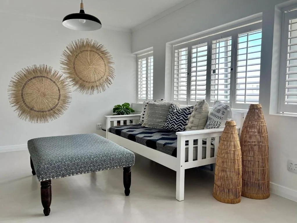 Bright bedroom with white bed, decorative woven wall art, and coastal decor