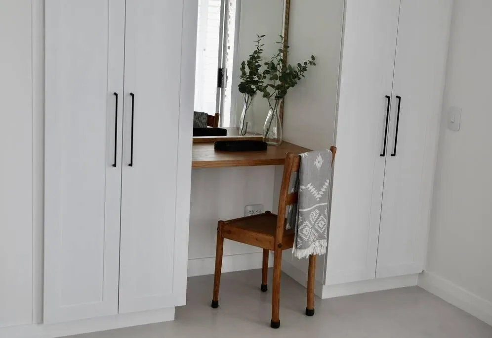 Bright bedroom with white built-in wardrobes and wooden vanity desk