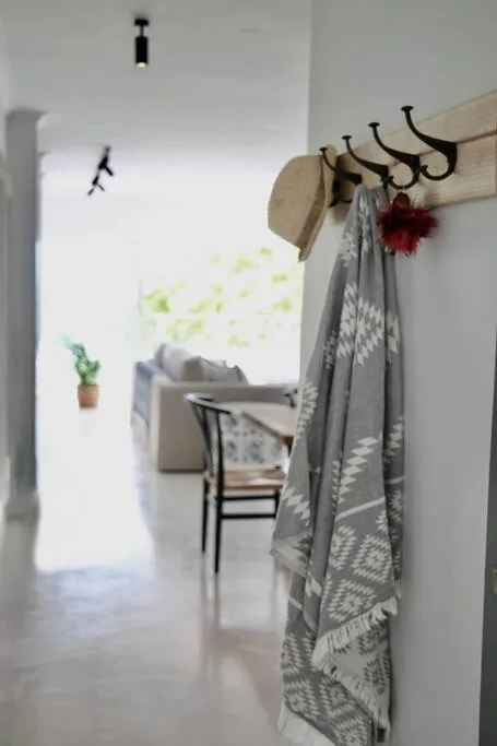 Wooden coat rack with hooks holding blankets and decorative items indoors