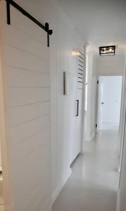Modern white hallway with sliding barn door and minimalist hardware fixtures