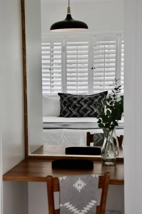 Modern workspace with wooden desk, black pendant light, and potted flowers