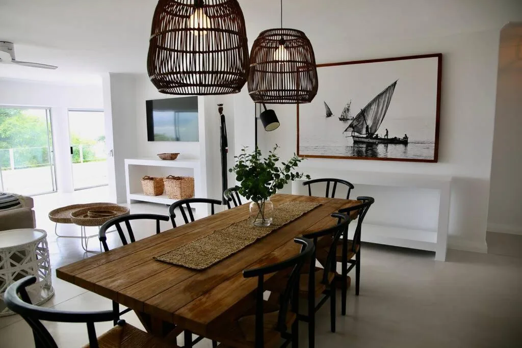 Wooden dining table with black chairs under woven pendant lights