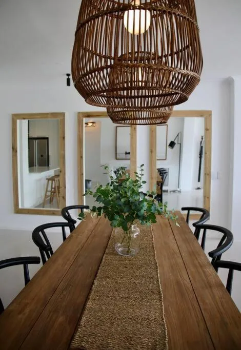 Wooden dining table with black chairs beneath woven pendant light fixture