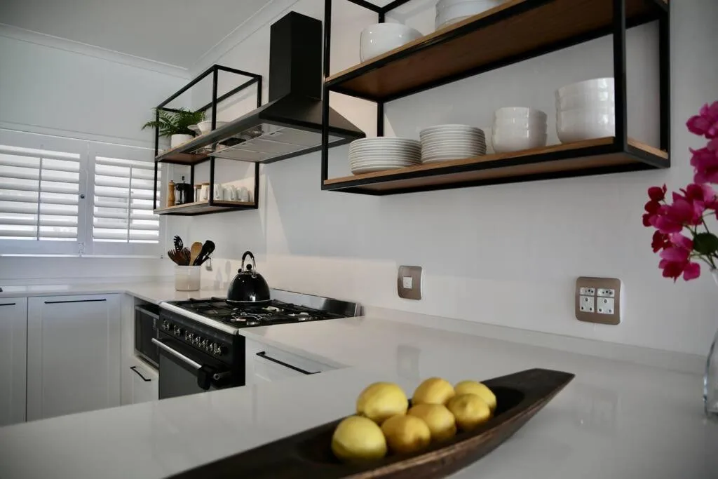 Modern kitchen with black gas stove, white counters, and open shelving