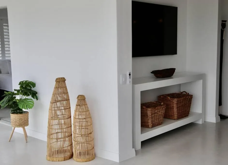 Modern lounge with wall-mounted TV, white console table, and decorative baskets