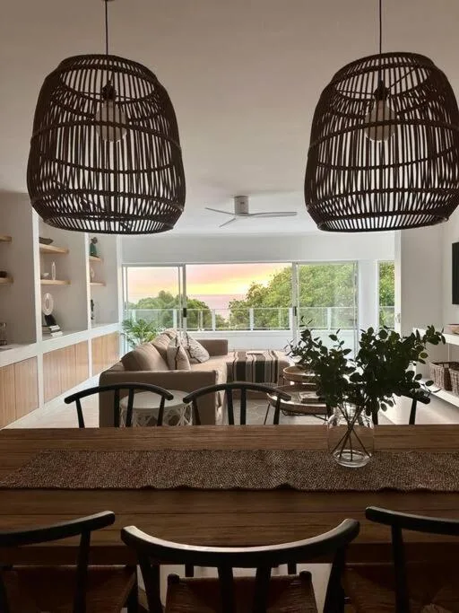 Modern lounge with woven pendant lights and sunset view through large windows