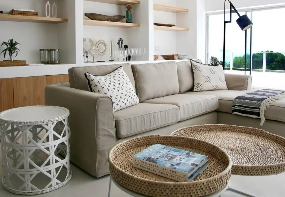 Spacious lounge with beige sofa, woven baskets, and coastal views