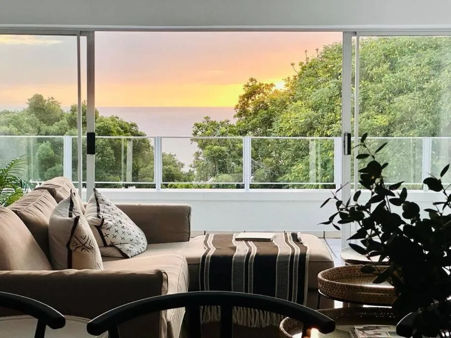 Modern lounge with sofa overlooking sunset ocean view through large windows