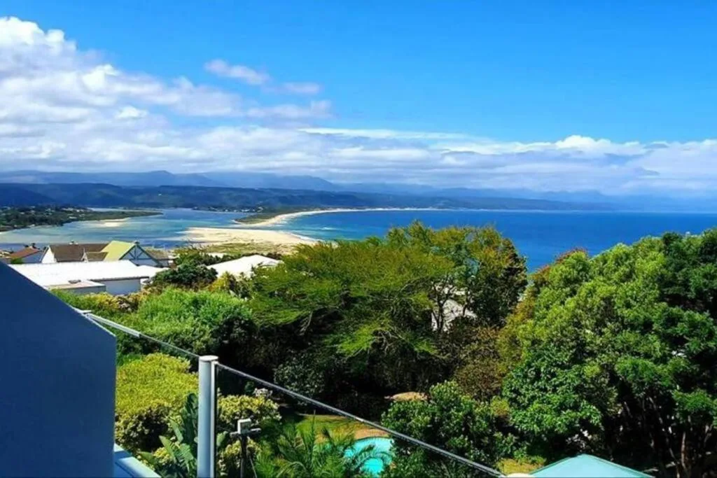 Panoramic coastal view of turquoise bay, white sandy beach, and distant mountains