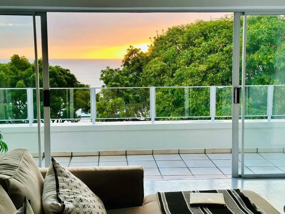 Ocean sunset view through deck windows with lush green trees