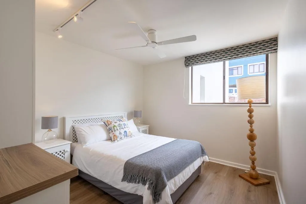 Bright bedroom with queen bed, white nightstands, and ceiling fan