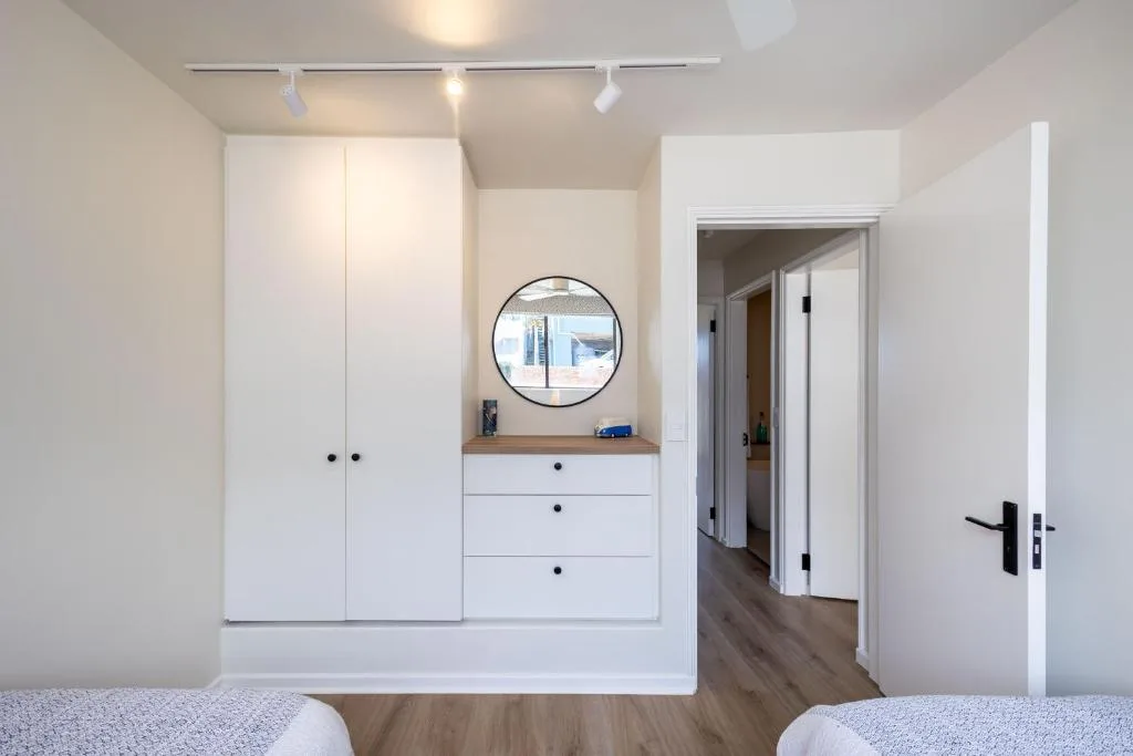 Modern bedroom with built-in white wardrobes and circular mirror vanity