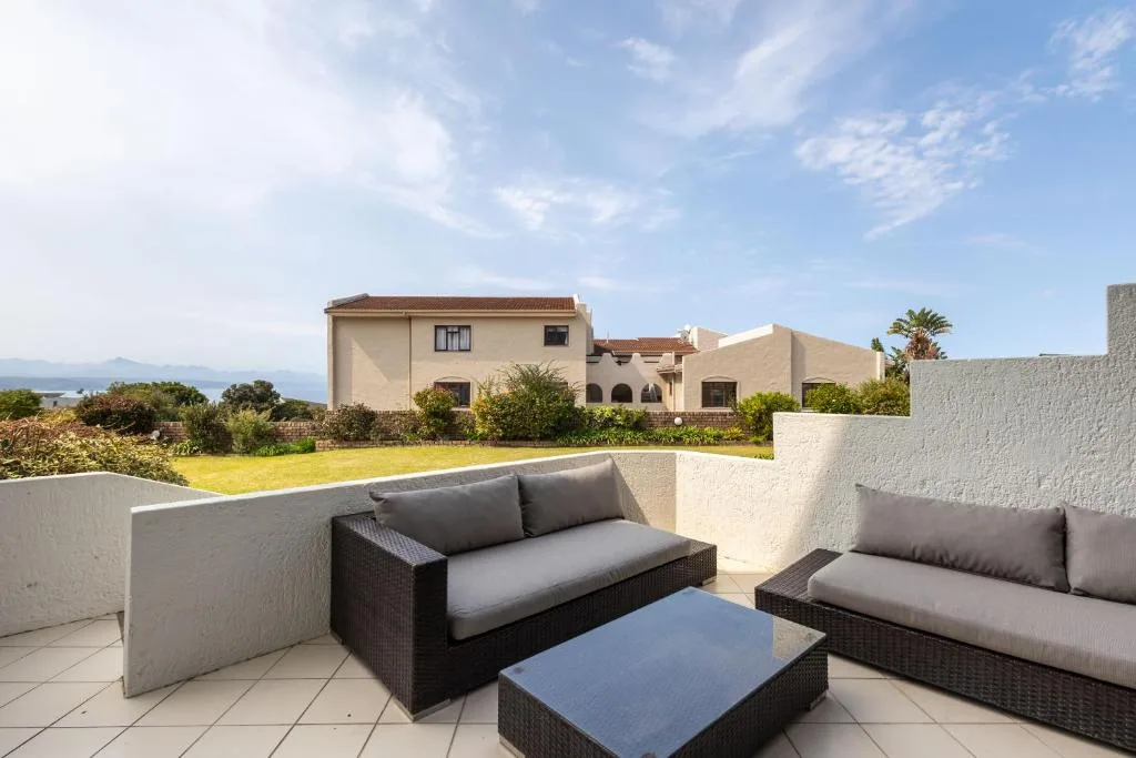 Outdoor patio with comfortable rattan seating and mountain views beyond