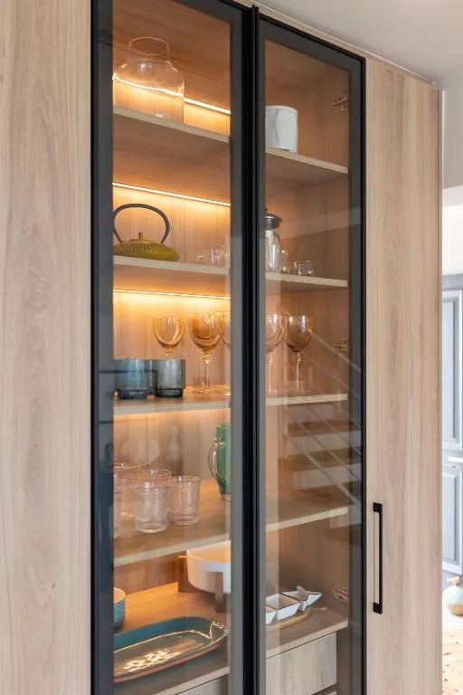 Modern glass display cabinet with warm lighting and glassware collection