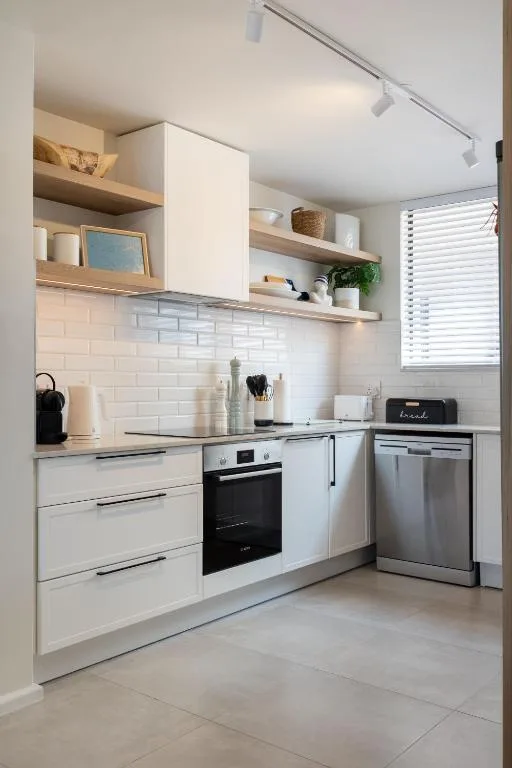 Modern white kitchen with built-in oven, dishwasher, and open shelving