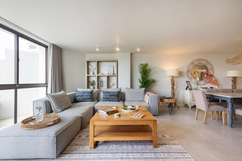 Bright, modern living room with gray sofa, wooden coffee table, coastal decor