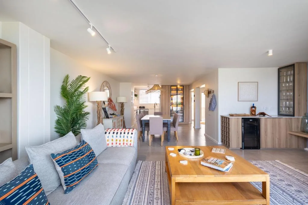 Modern lounge with grey sofa, wooden coffee table, and open-plan dining area beyond