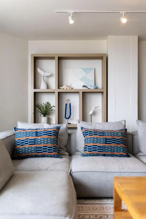 Modern lounge with gray sofa, blue patterned pillows, and wall shelving display