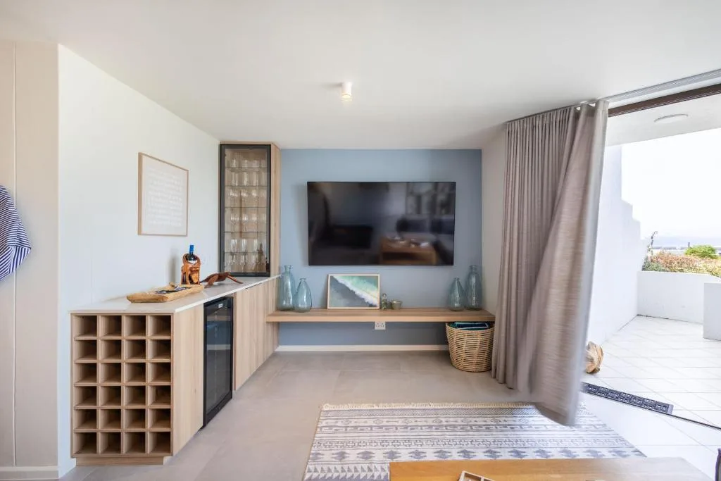 Modern living room with wall-mounted TV, blue accent wall, and open kitchen area