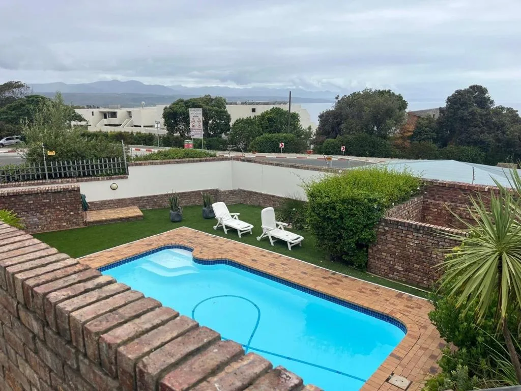 Bright blue swimming pool with loungers and mountain views beyond