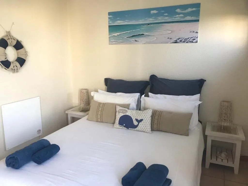 Coastal-themed bedroom with white bedding, navy pillows, and beach artwork