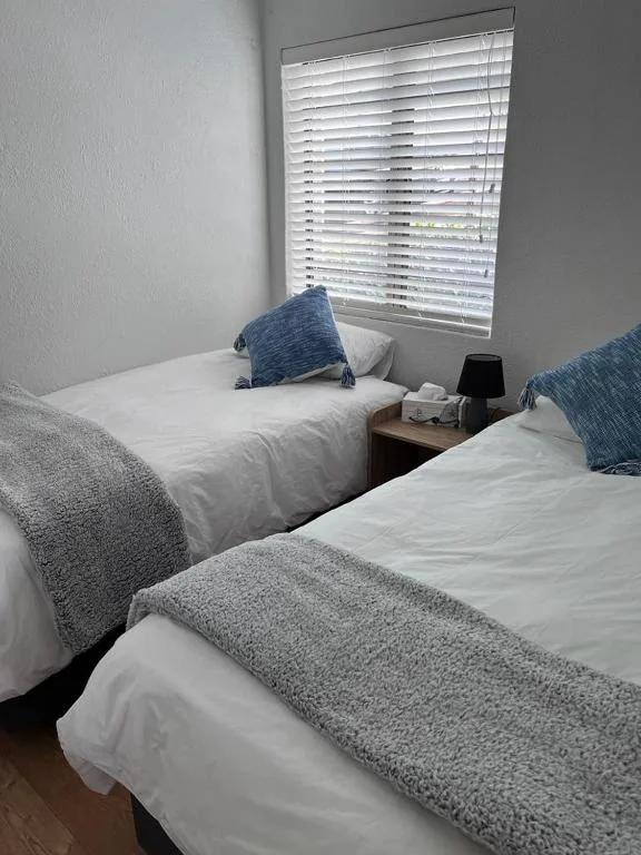 Twin beds with white linens and blue throw pillows in bright bedroom