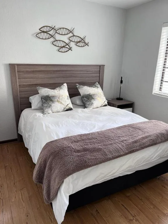 Bedroom with wooden headboard, white bedding, and decorative fish wall art
