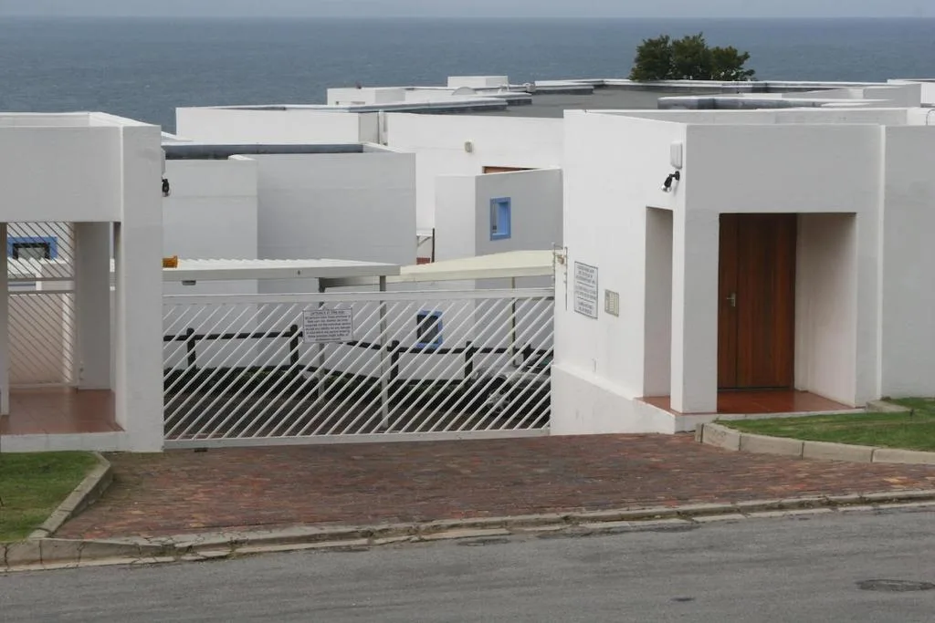 Modern white apartment building with metal gate and ocean view backdrop