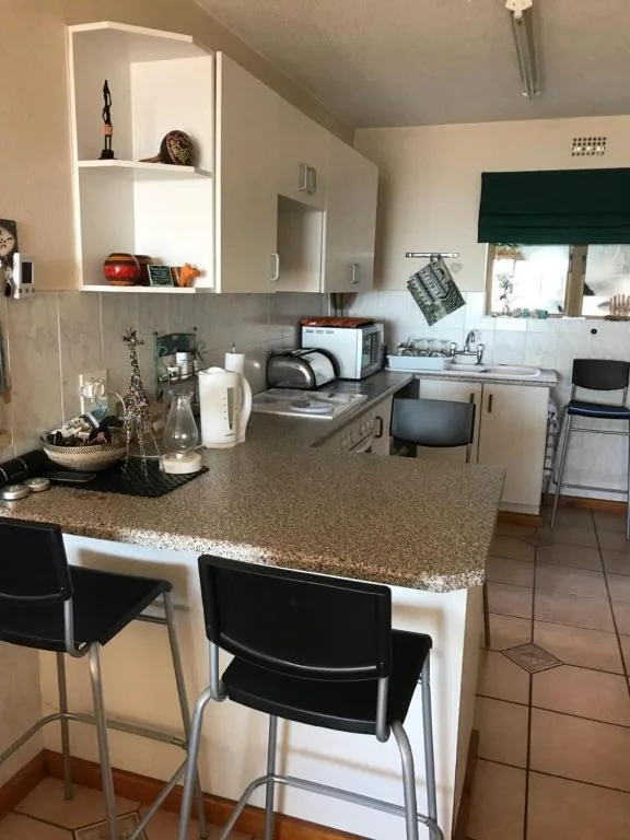 Modern kitchen with granite countertop, stove, and white cabinetry
