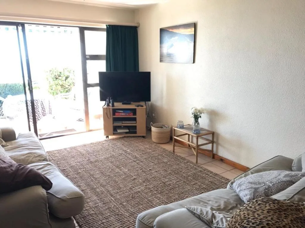 Bright lounge with TV, comfortable seating, and glass doors to outdoor deck