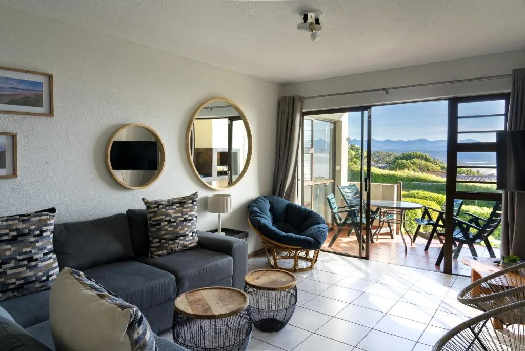 Modern lounge with black sofa, round mirrors, ocean views through glass doors
