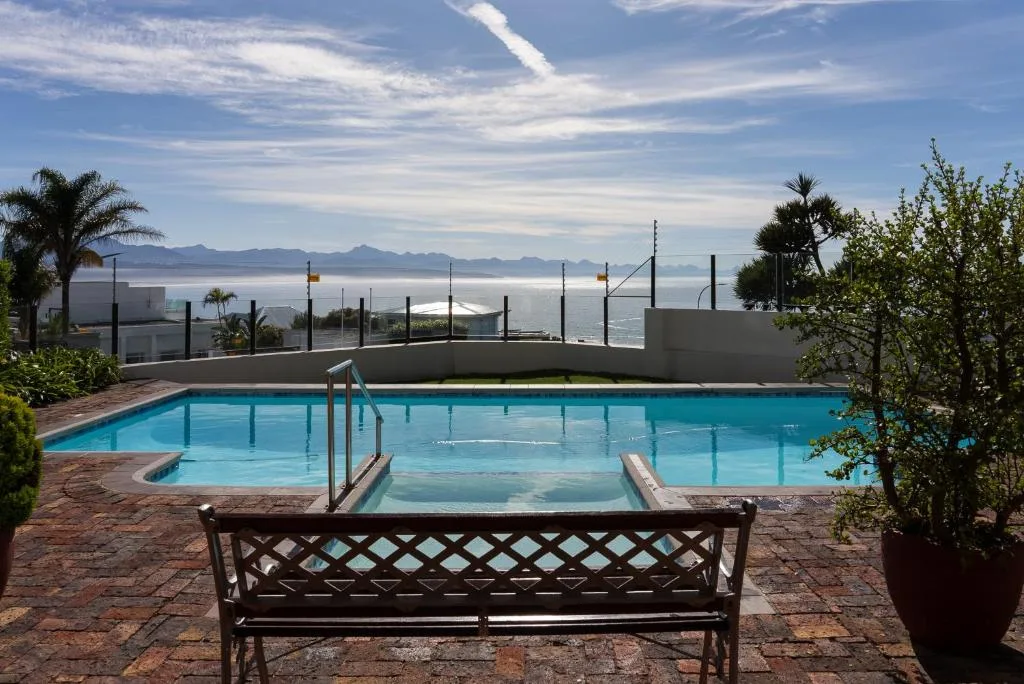 Swimming pool with ocean and mountain views beyond safety fencing