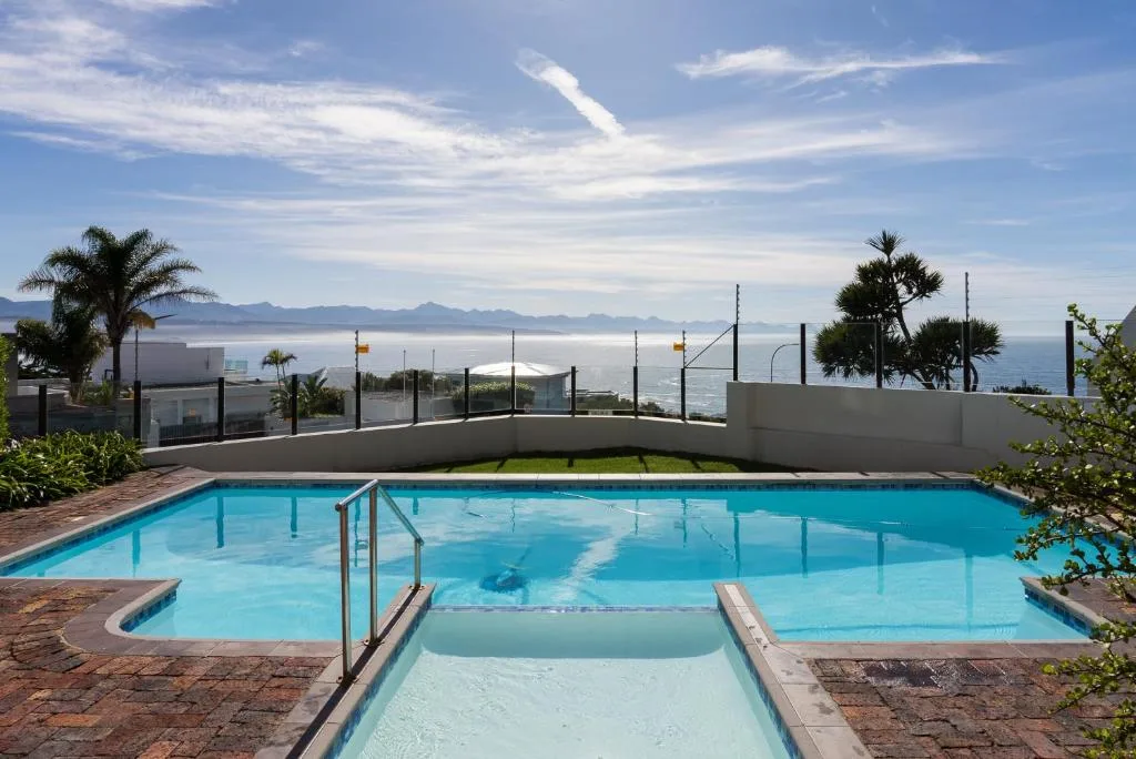 Sparkling blue swimming pool with ocean and mountain views beyond