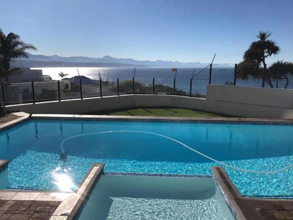 Swimming pool with ocean and mountain views in background