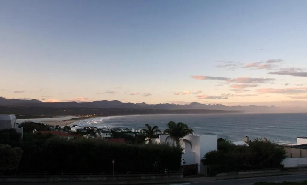 Sunset ocean view over Plettenberg Bay with mountains and coastal town