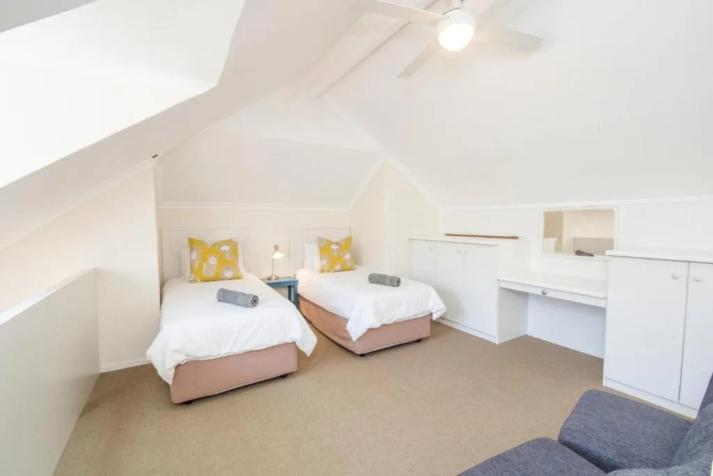 Bright attic bedroom with two single beds and yellow pillows