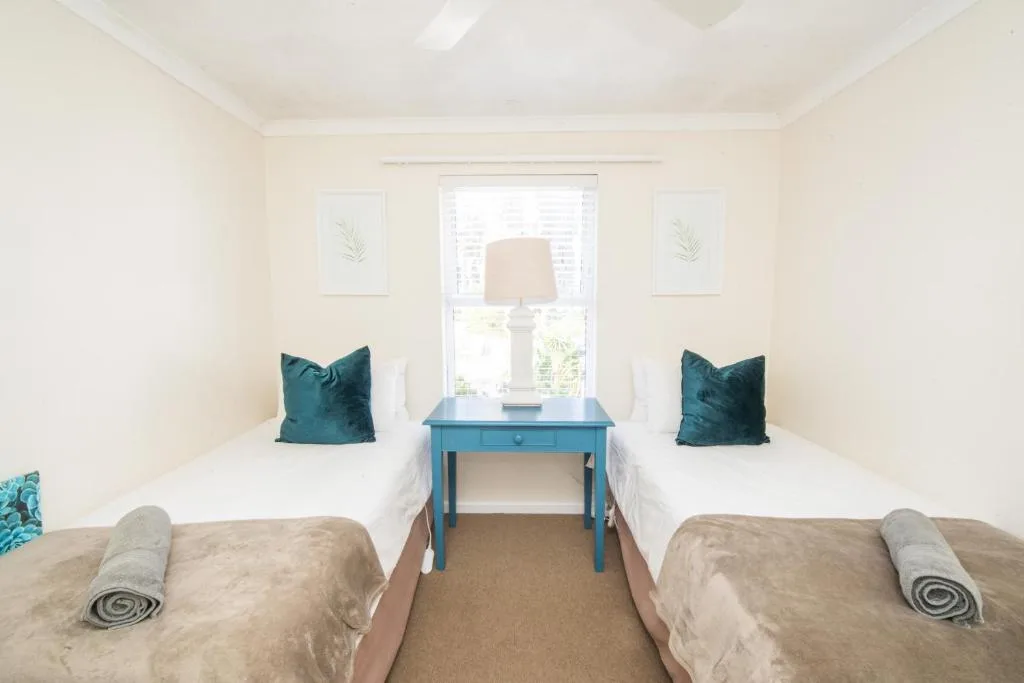 Bright twin bedroom with teal accents and natural light from window