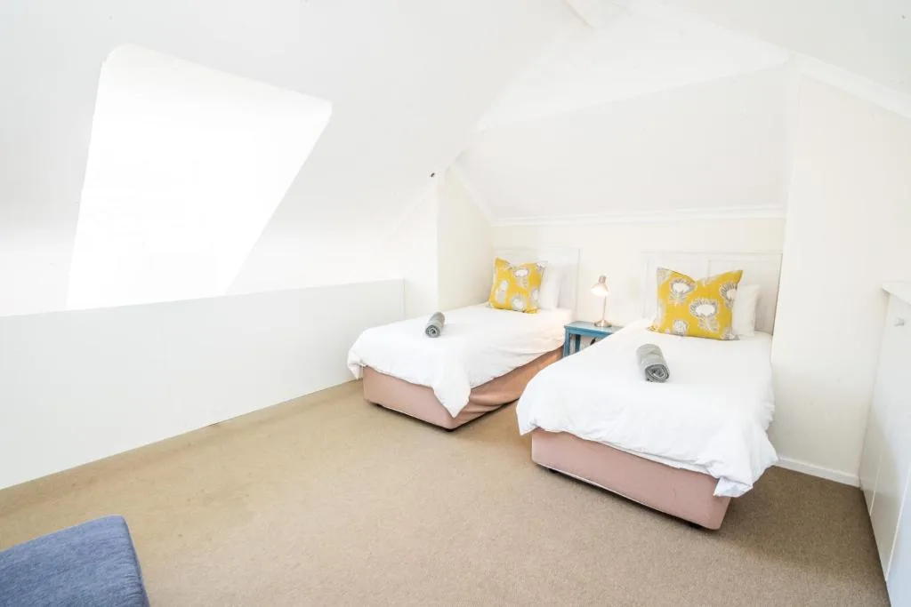 Bright twin bedroom with yellow accent pillows and skylight window