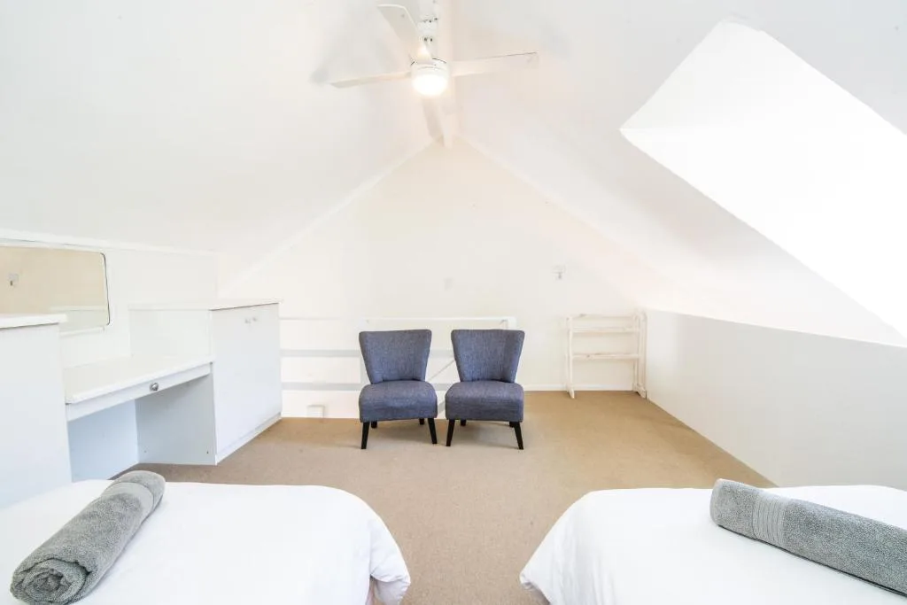 Bright attic bedroom with two beds and comfortable seating area